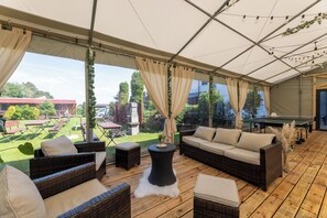 An outdoor patio with wicker furniture, a round table, and a view of the garden.