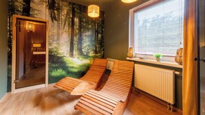 A room with a wooden bench, a radiator, a window with blinds, and a forest mural on the wall. - Awilla (Ustka)
