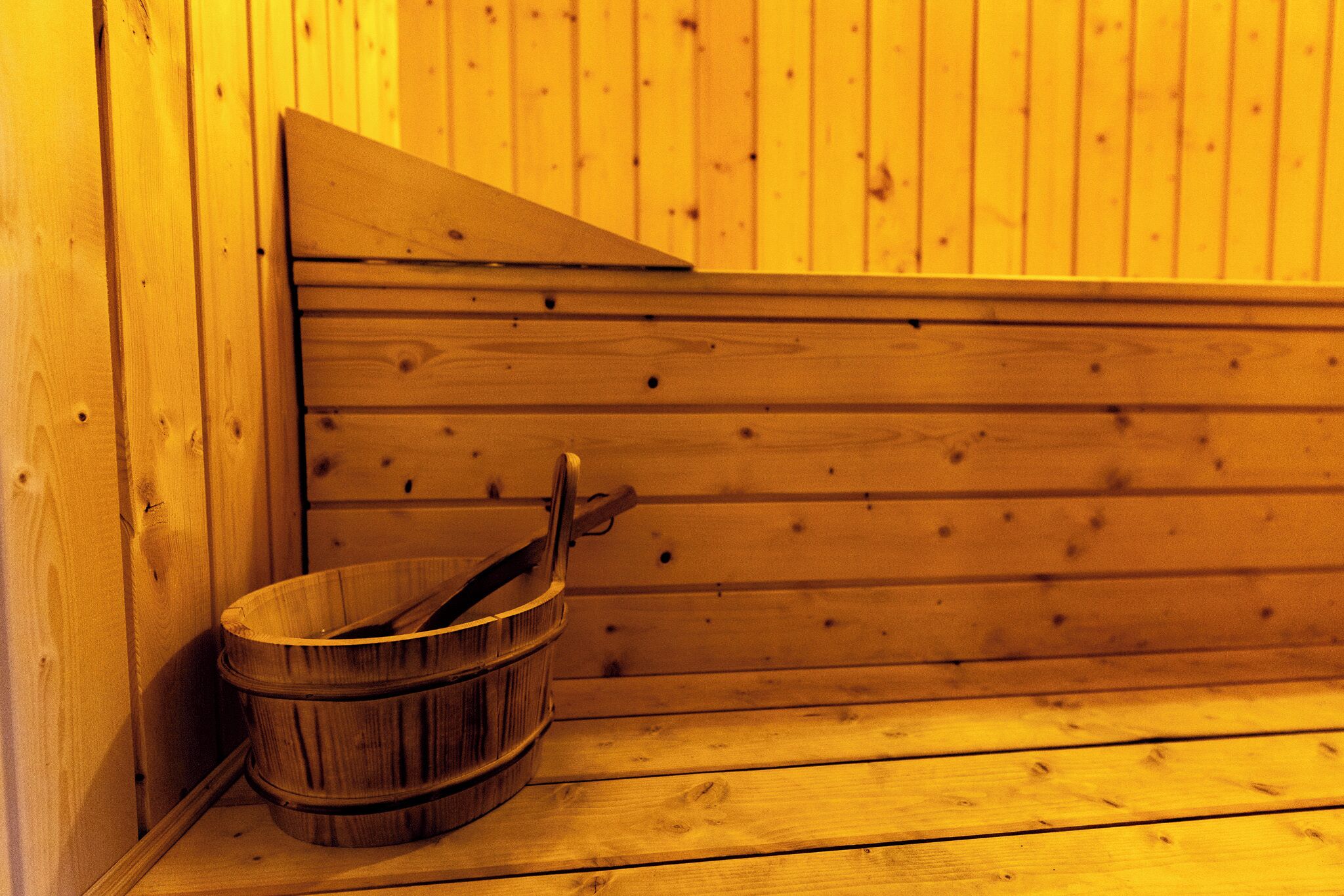 A wooden sauna with a wooden bucket and a wooden bench.