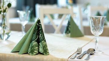 A table set with a green napkin, a glass, and cutlery.