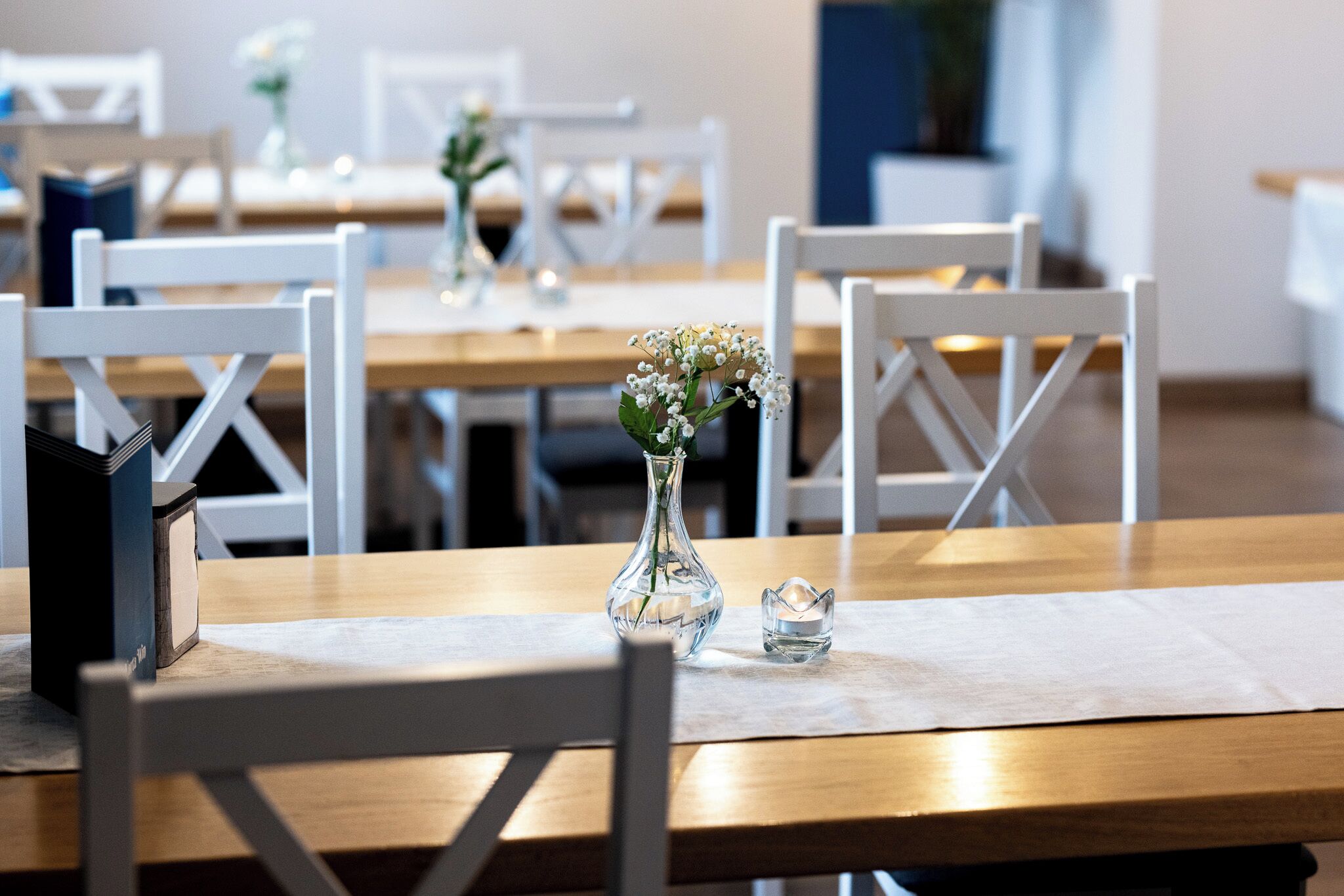 A dining area with wooden tables and white chairs.