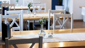 A dining area with wooden tables and white chairs.