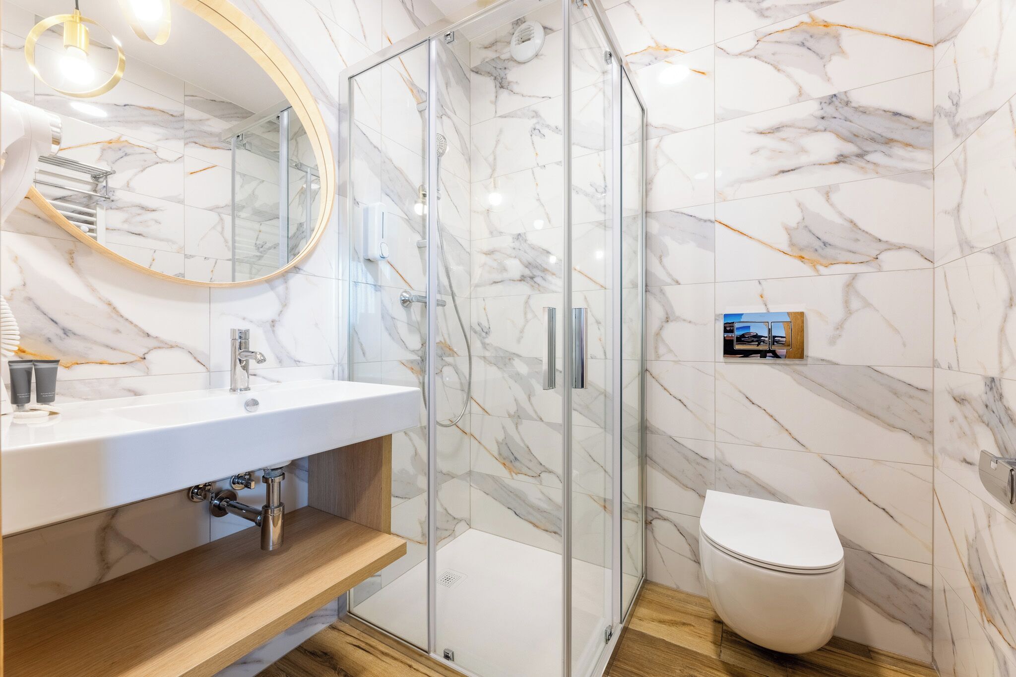 A modern bathroom with a glass shower enclosure, a white sink, and a toilet.