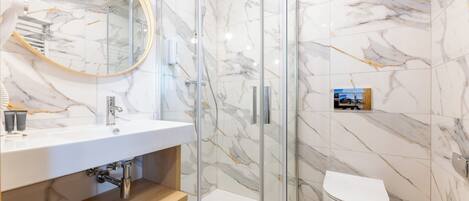 A modern bathroom with a glass shower enclosure, a white sink, and a toilet.