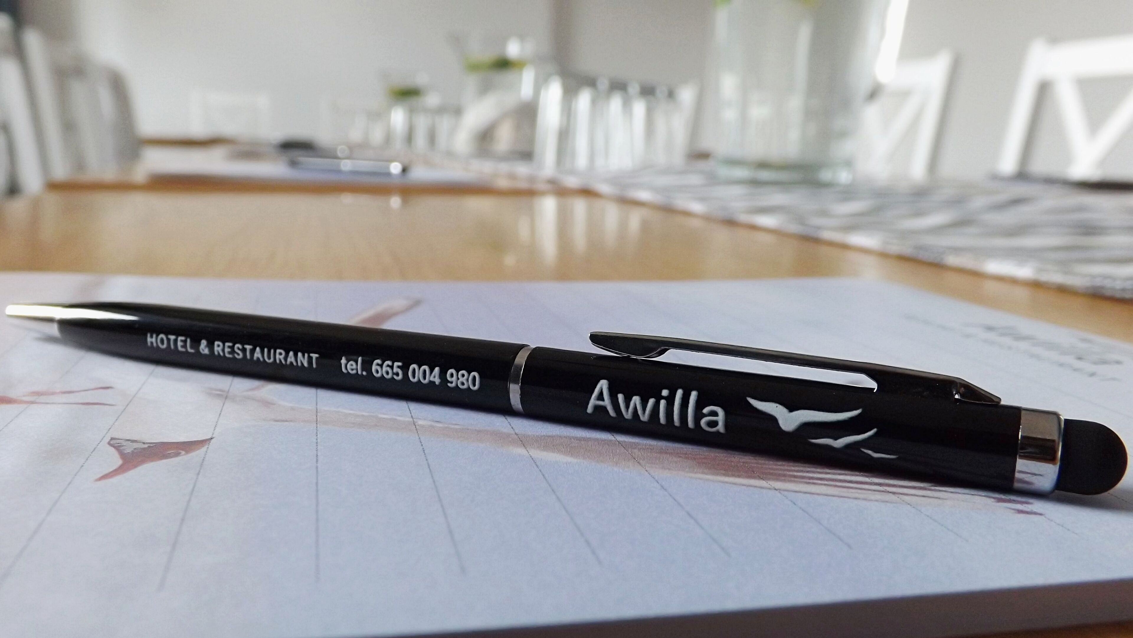 Un stylo sur une table, à côté d’une brochure d’hôtel.