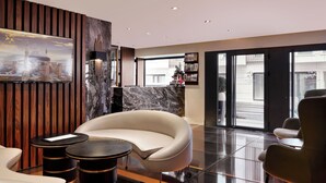 A modern lobby with a curved white sofa, a marble reception desk, and a large window offering a city view. - Shining Star Hotel (Istanbul)