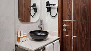 A bathroom with a wooden door, a mirror, a sink with a black basin, and a towel rack.
