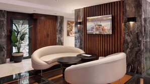 A modern lobby with a curved white sofa, a glass coffee table, and a potted plant. - Shining Star Hotel (Istanbul)