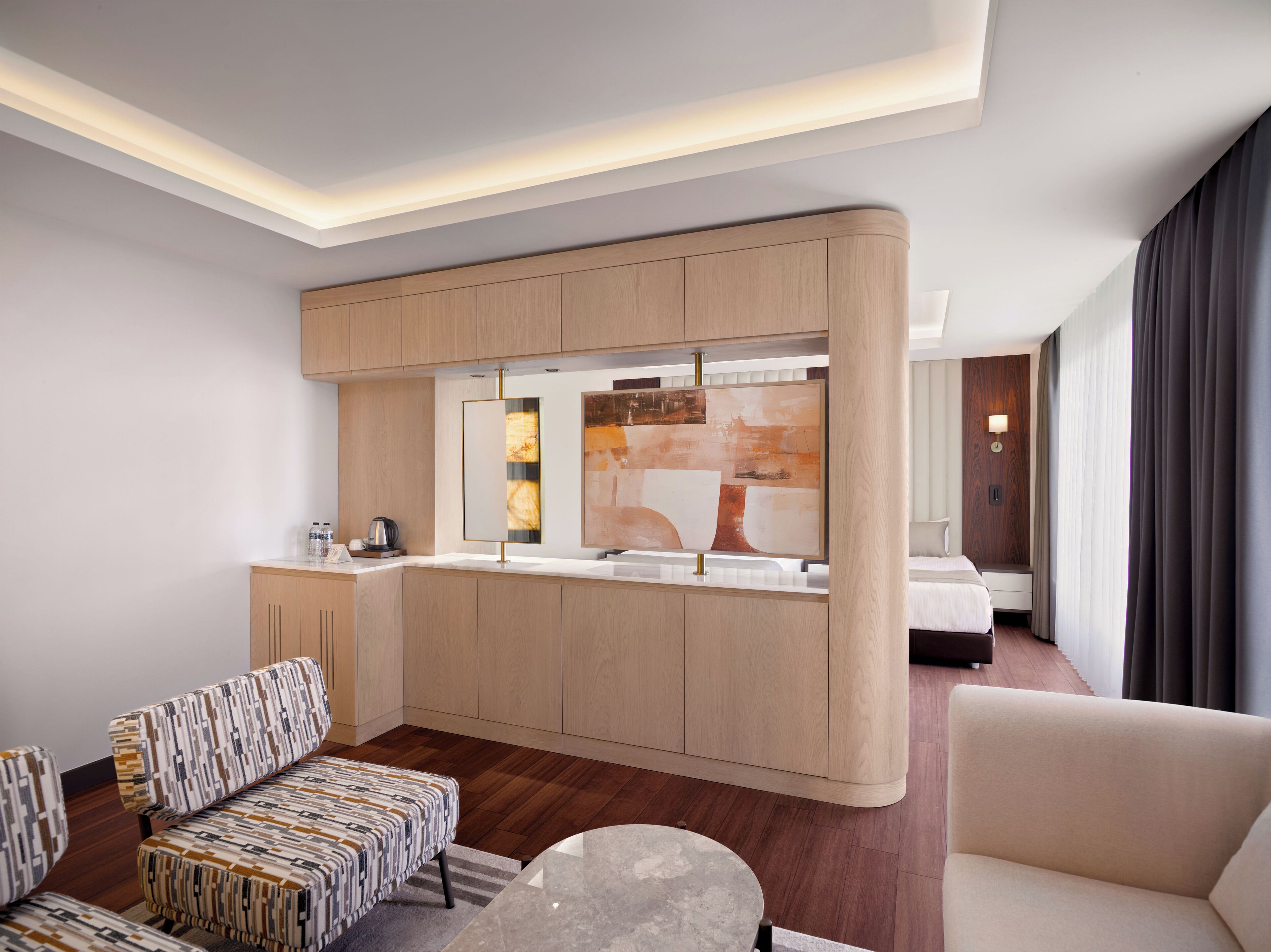 A modern hotel room with a kitchenette, a sofa, a coffee table, and a bed.