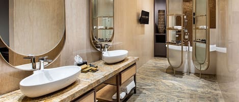 A modern bathroom with two large sinks, a mirror, and a shower enclosure.
