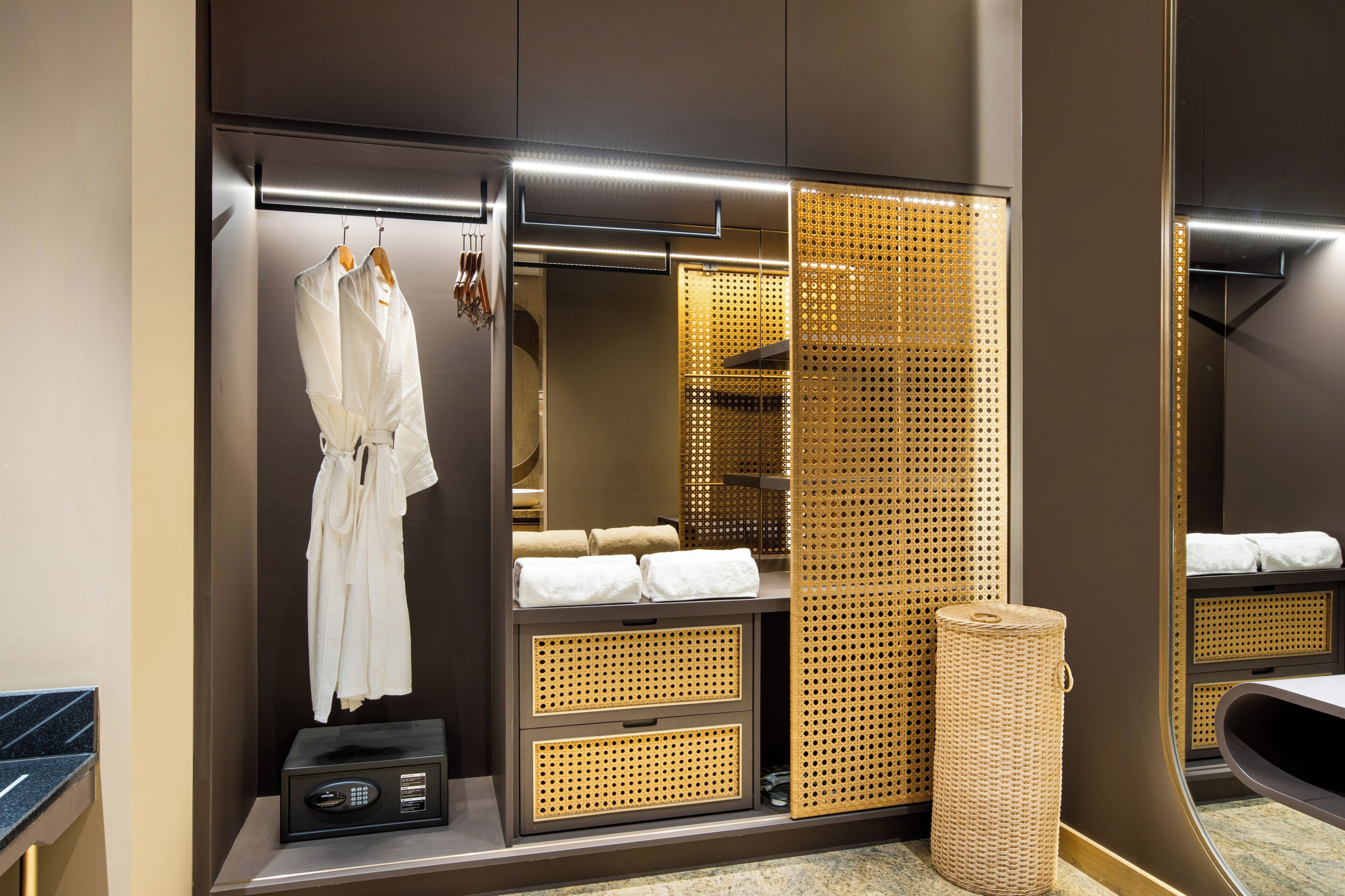 Ein modernes Badezimmer mit großem Spiegel, Handtuchhalter, Duschbereich und Mülleimer.