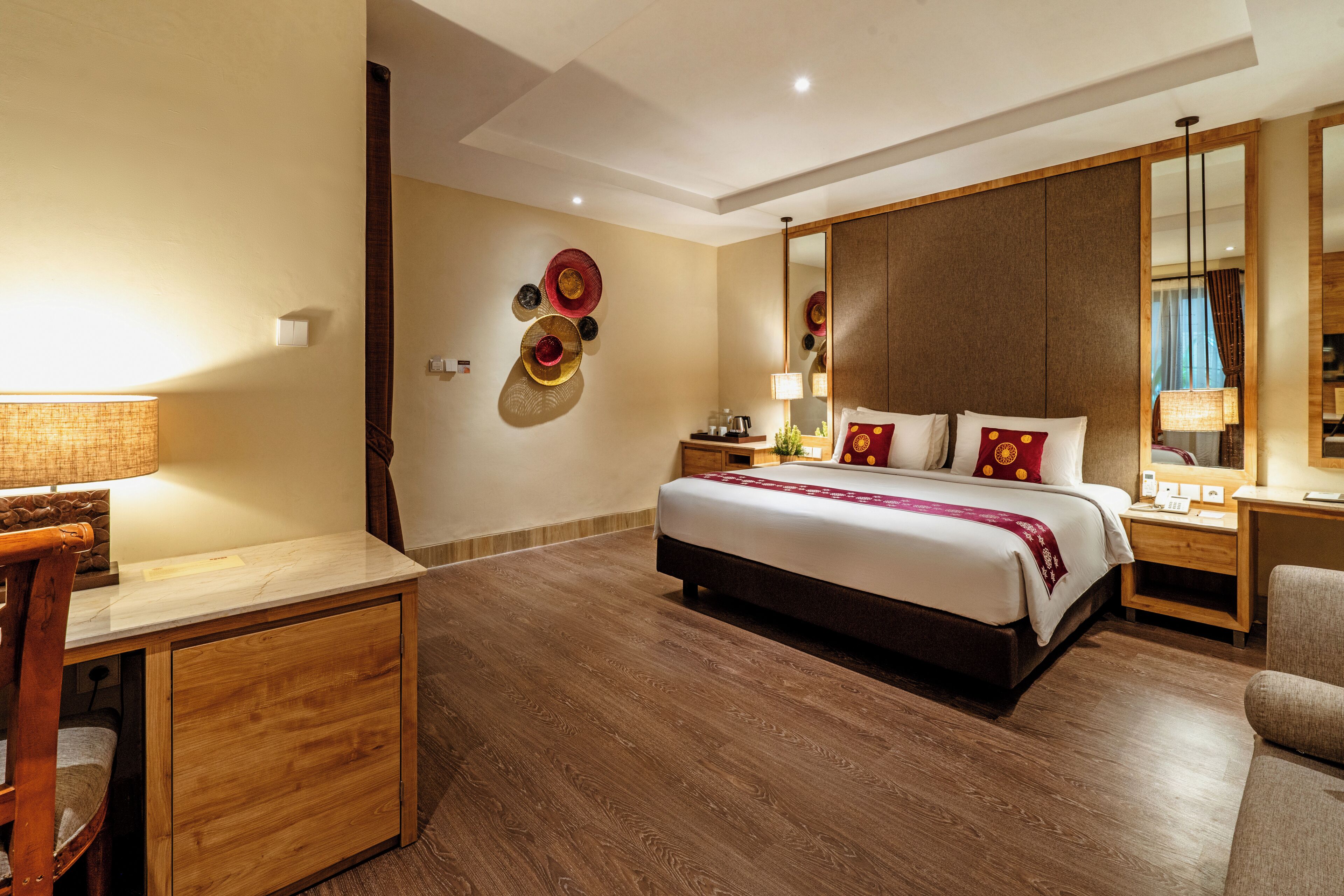 Een hotelkamer met een bed, een bureau, een stoel, een nachtkastje, een lamp en een spiegel.