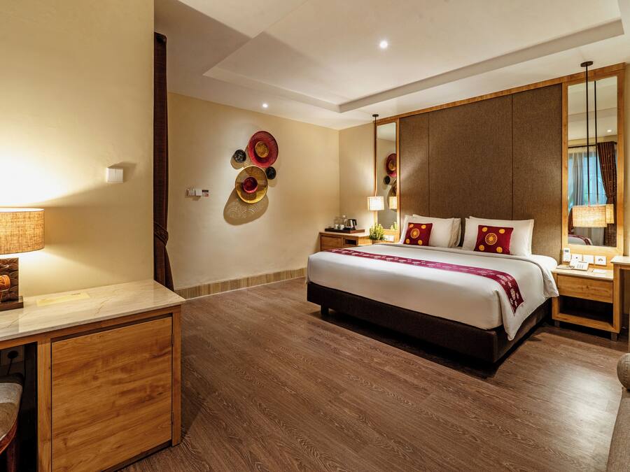 Een hotelkamer met een bed, een bureau, een stoel, een nachtkastje, een lamp en een spiegel.