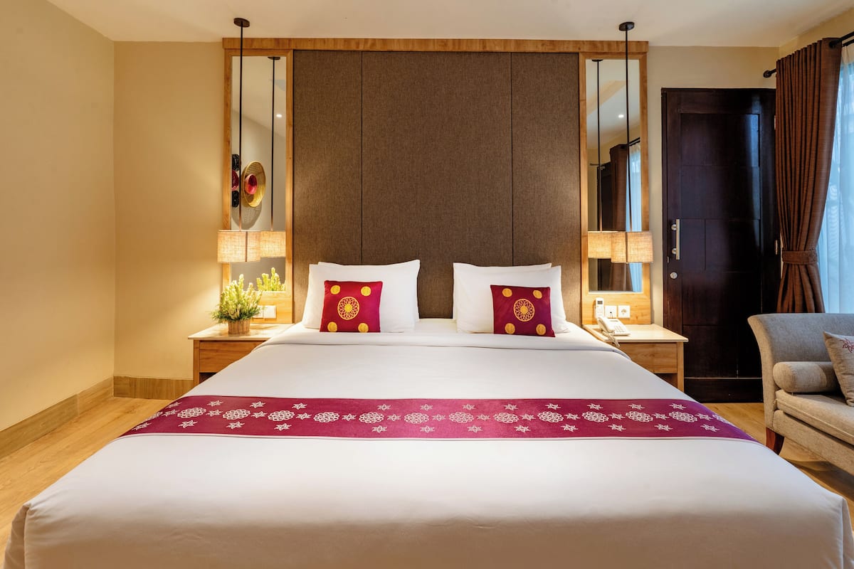 A hotel room with a large bed, two bedside tables with lamps, a mirror, and a chair.
