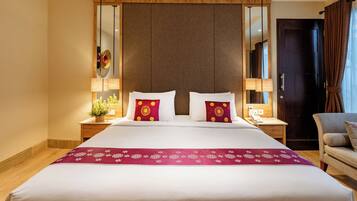 A hotel room with a large bed, two bedside tables with lamps, a mirror, and a chair.