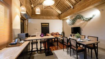A modern dining area with wooden tables and chairs, a television, and a decorative wall piece.