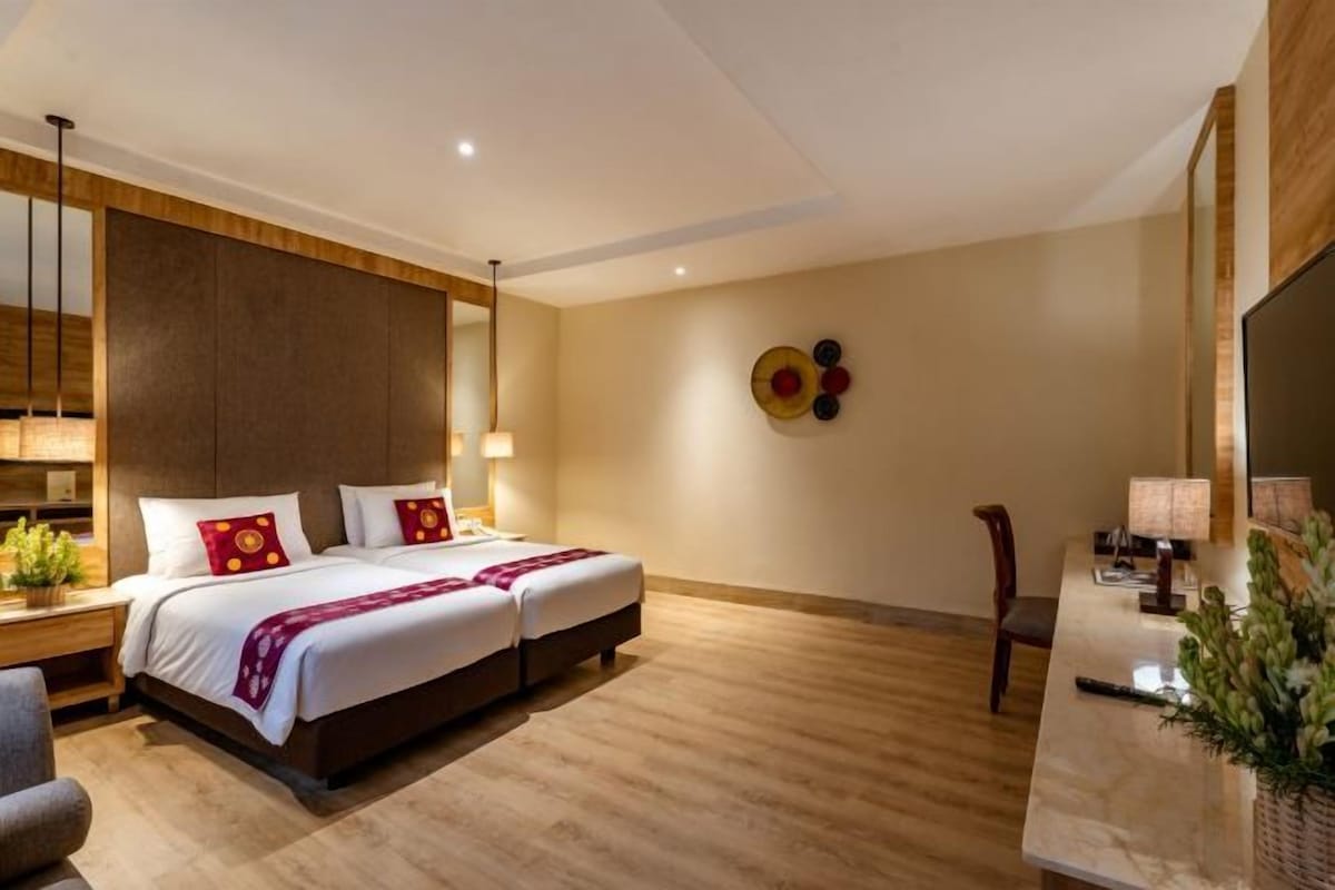 A modern hotel room with a large bed, bedside tables, a desk, and a mirror.