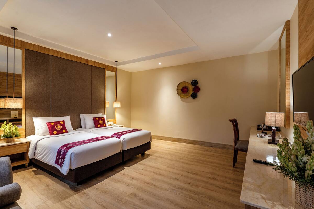 A modern hotel room with a large bed, bedside tables, a desk, and a chair.
