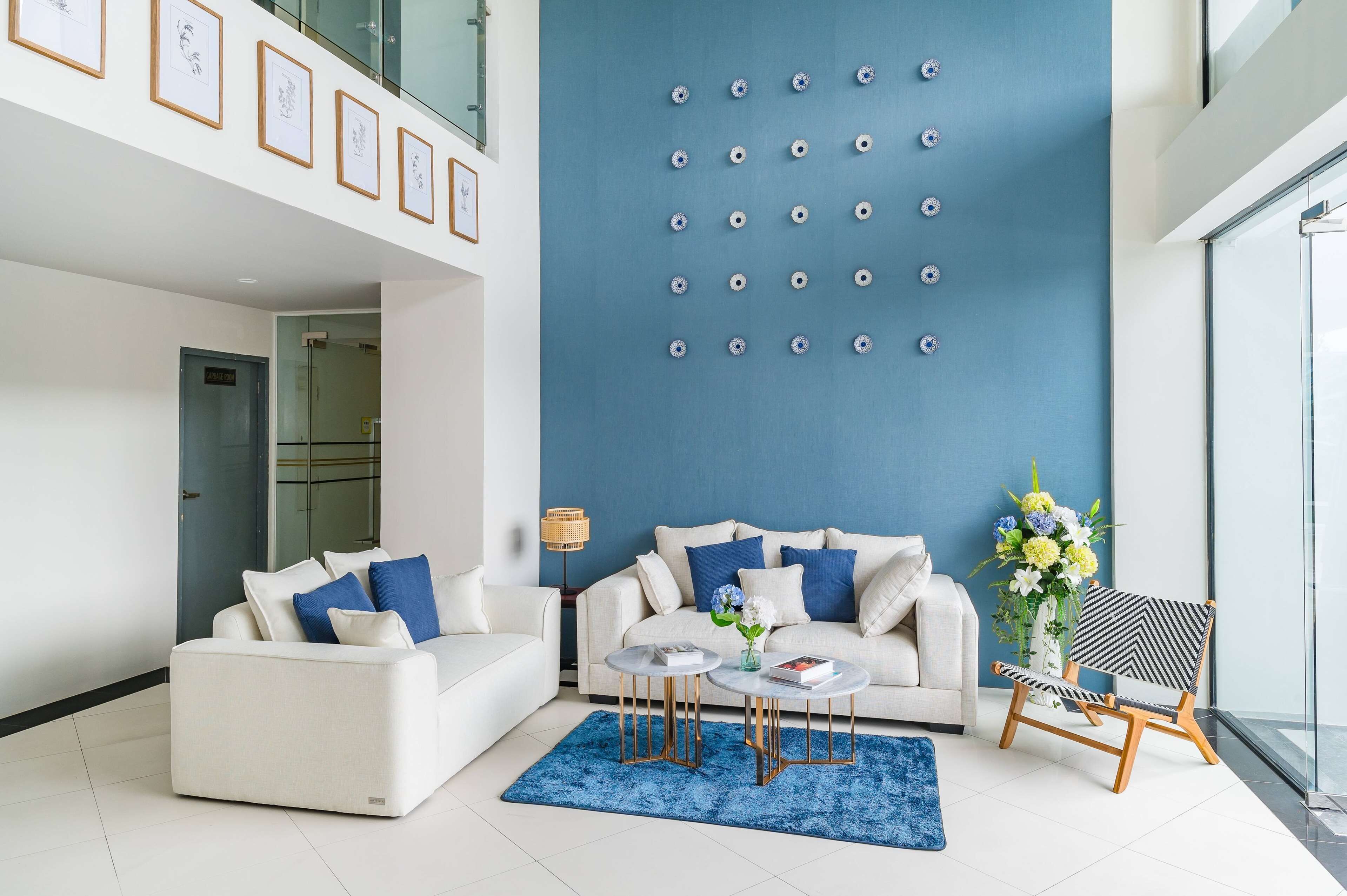 A modern living room with a white sofa, two round coffee tables, a blue rug, and a decorative chair.