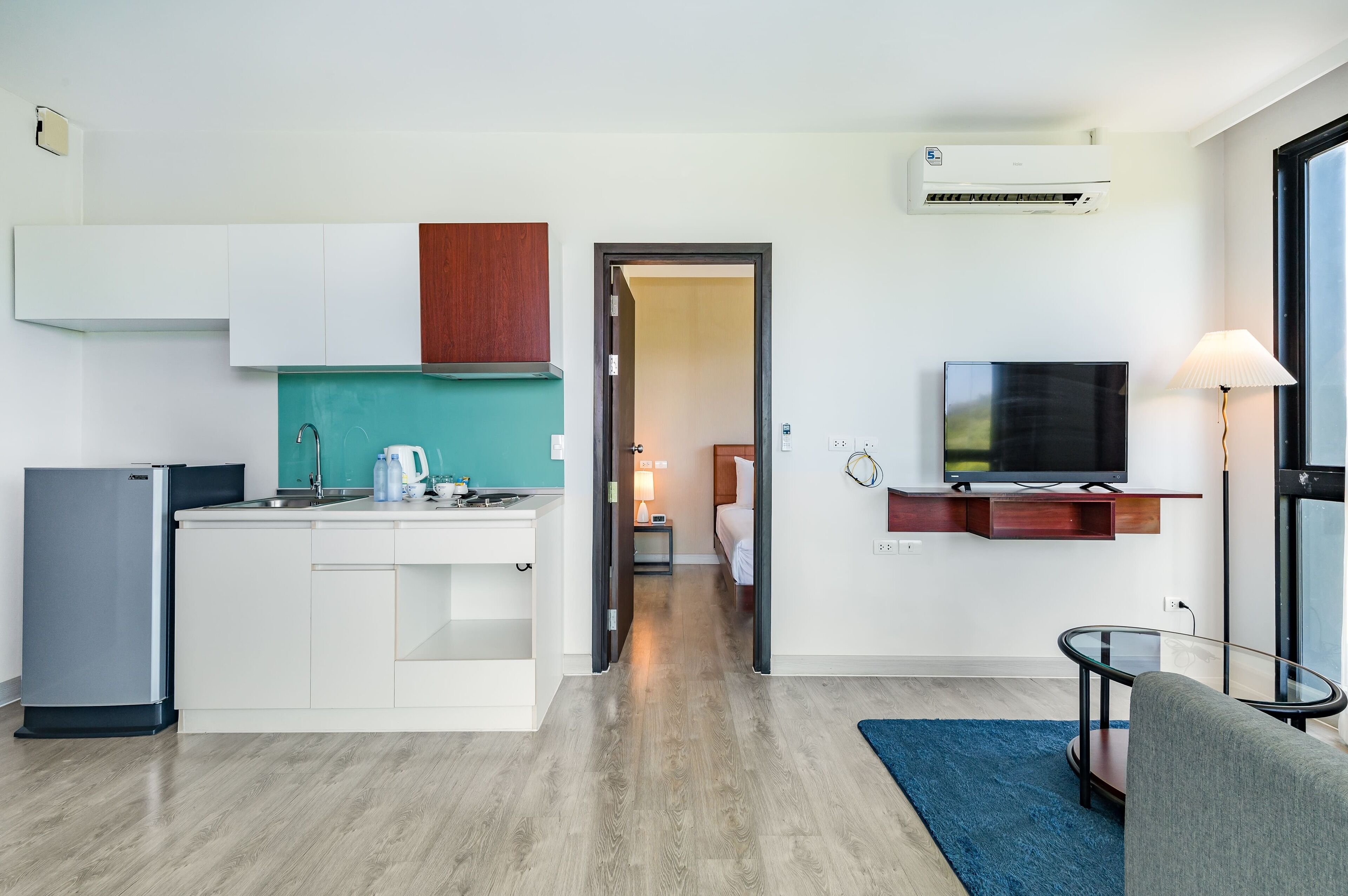Een compacte woonruimte met een kitchenette, een flatscreen televisie en een klein zithoekje.