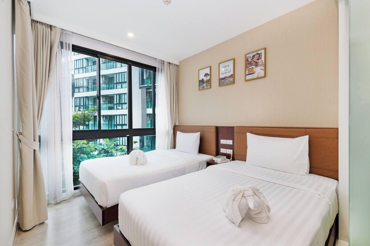 Ein Hotelzimmer mit zwei Betten, einem großen Fenster und Blick auf ein Gebäude.