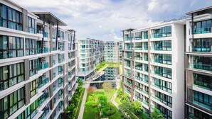 Un moderno edificio residencial de varios pisos con amplios ventanales, un patio central y cielo despejado.