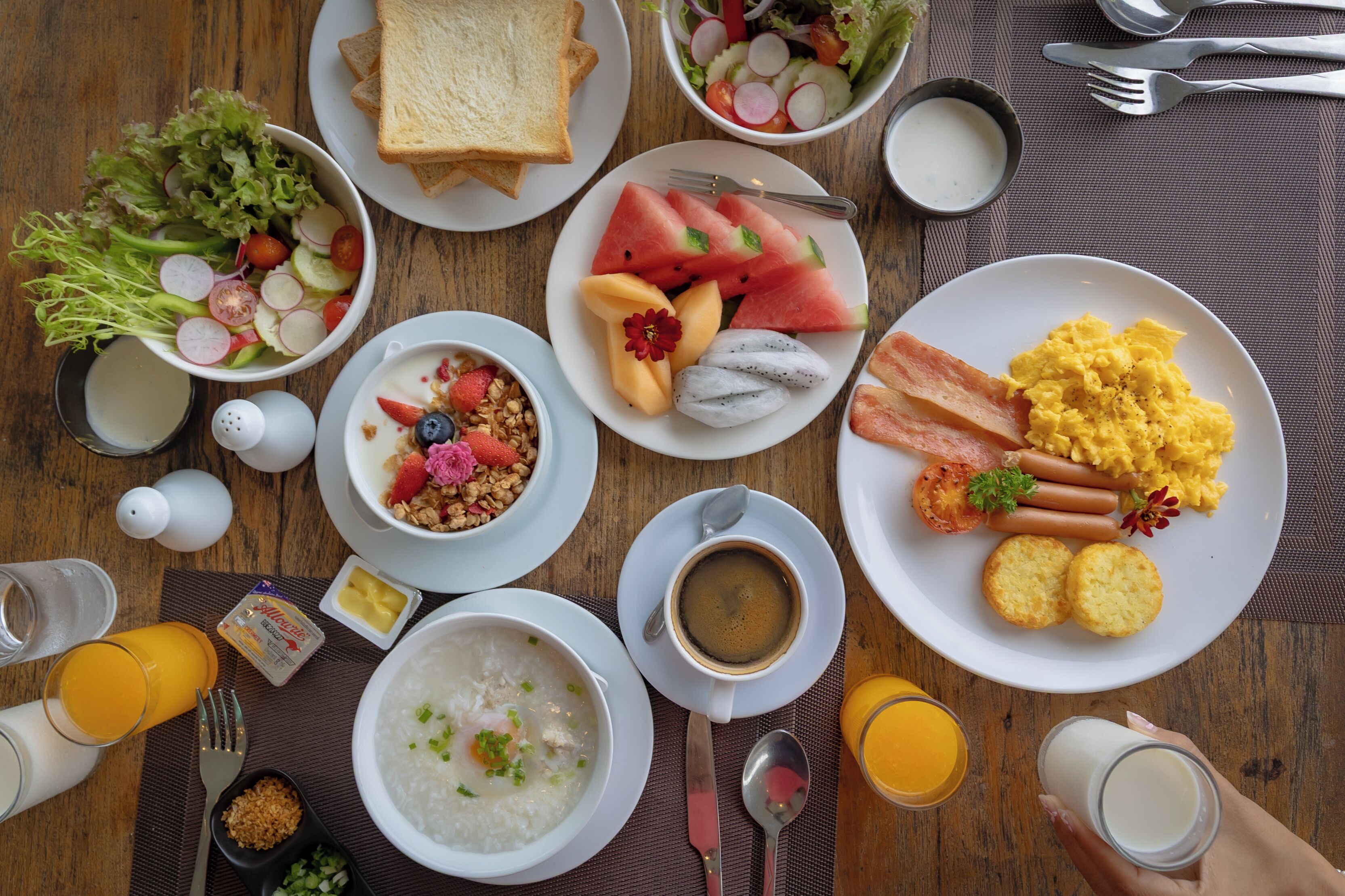 Impostazione colazione con diversi piatti, tra cui pane tostato, frutta, uova e una ciotola di zuppa.