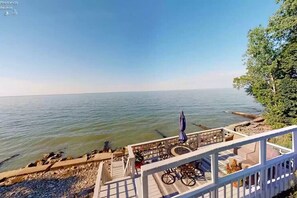 A coastal view with a wooden deck, outdoor seating, and a railing overlooking the sea.
