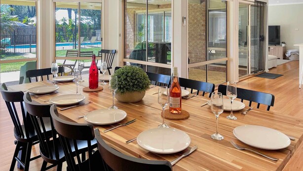 A dining area with a wooden table set for six, surrounded by black chairs. - Tallowood House - A great family getaway (NULKABA)
