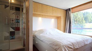 Une chambre avec un lit, une douche et une fenêtre donnant sur des arbres.