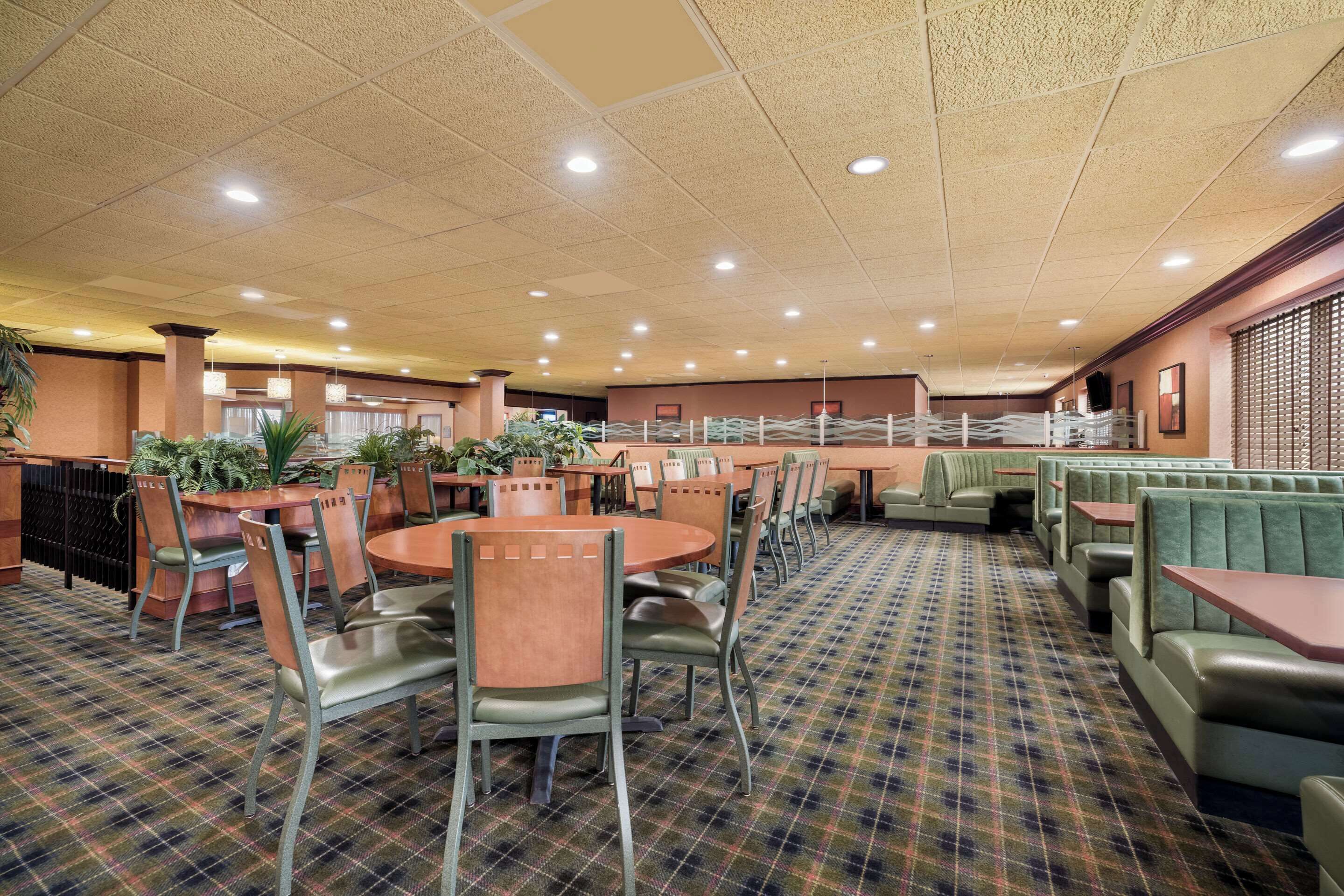 A restaurant with round tables, green upholstered booths, and a checkered floor.