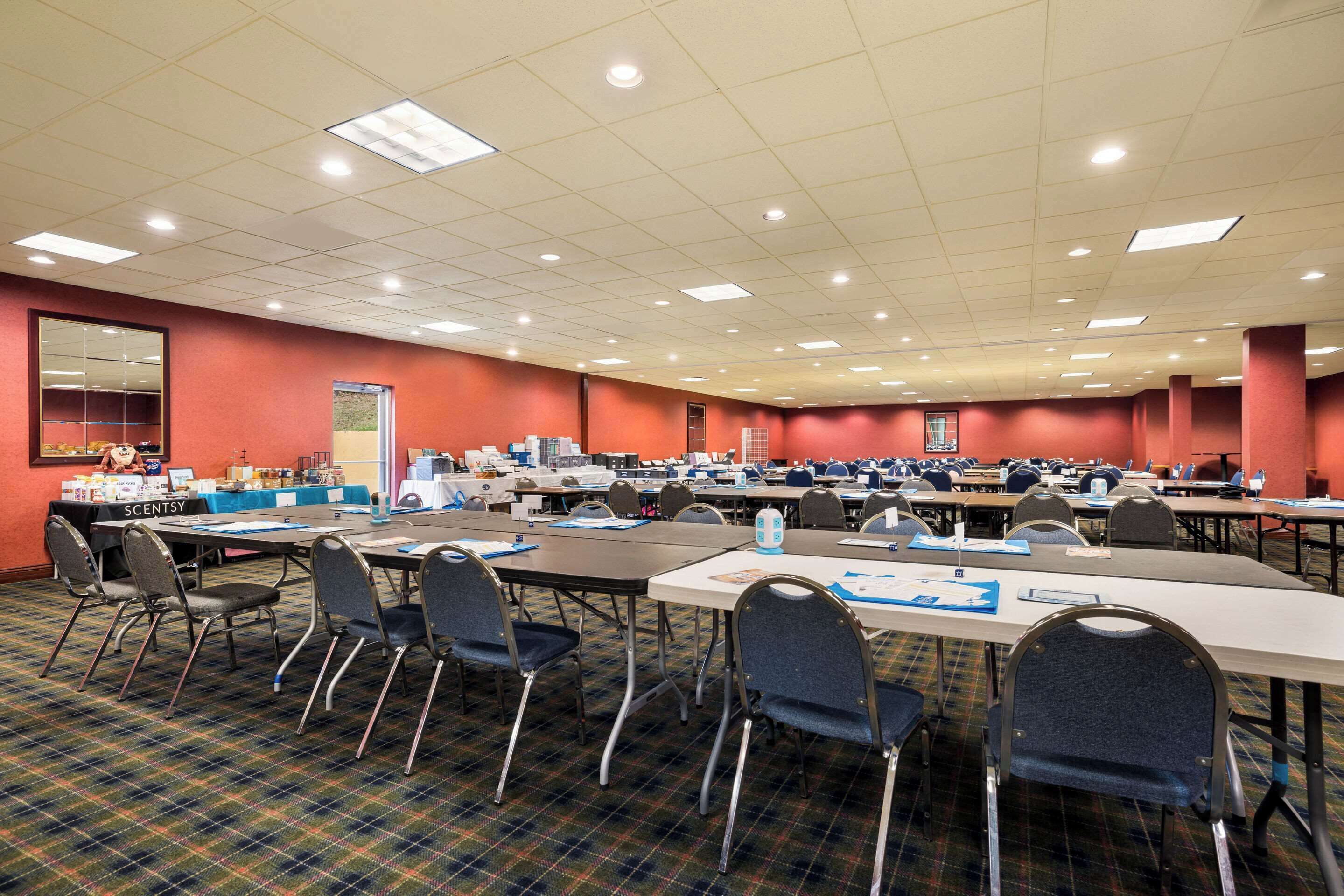 Une grande salle de conférence dotée de nombreuses tables et chaises, ainsi que de plaques nominatives et de bouteilles d’eau.