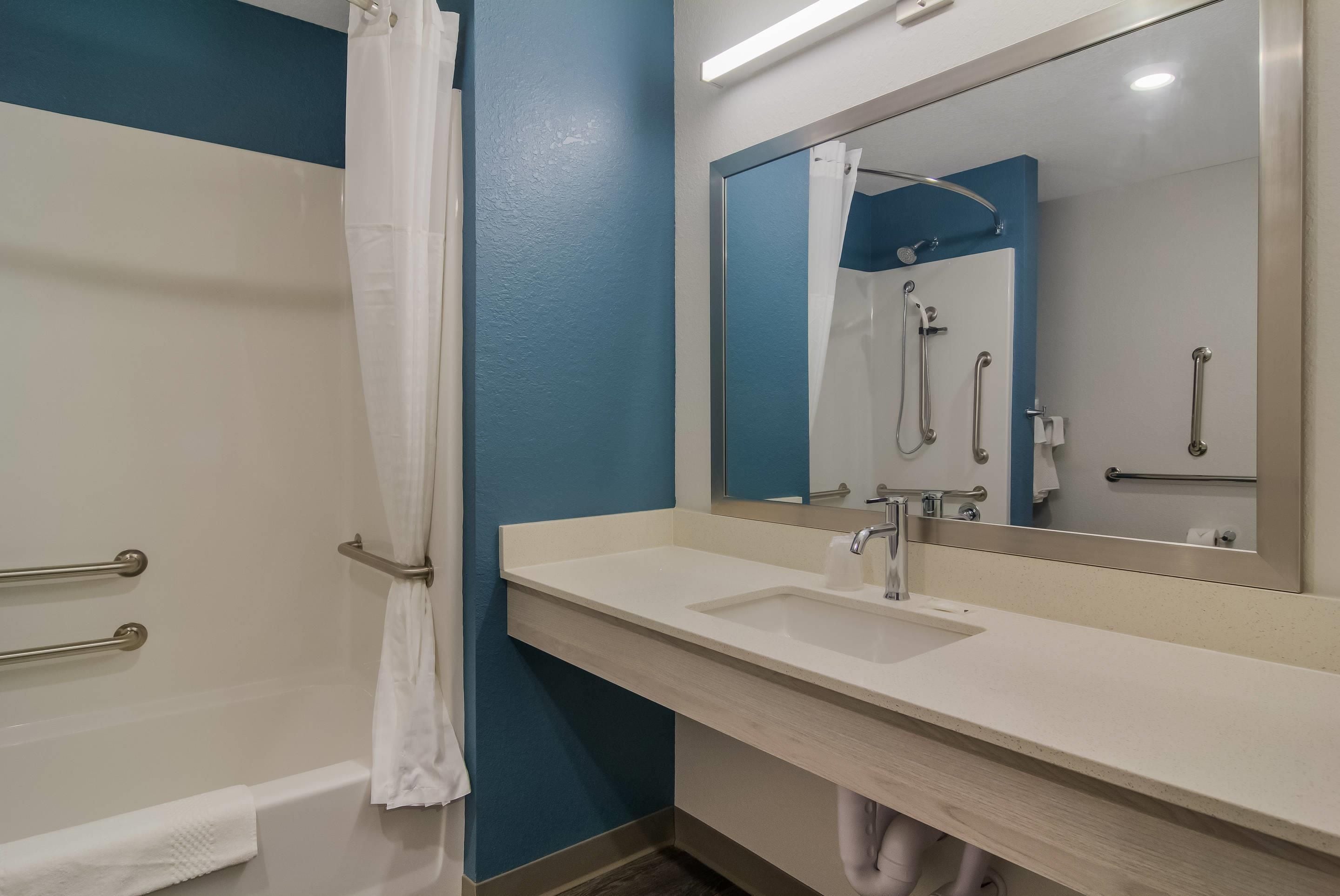 A bathroom with a shower, a sink, and a mirror.