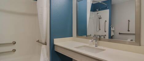 A bathroom with a shower, a sink, and a mirror.