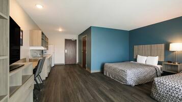 A modern hotel room with a desk, two beds, a TV, and a bathroom.