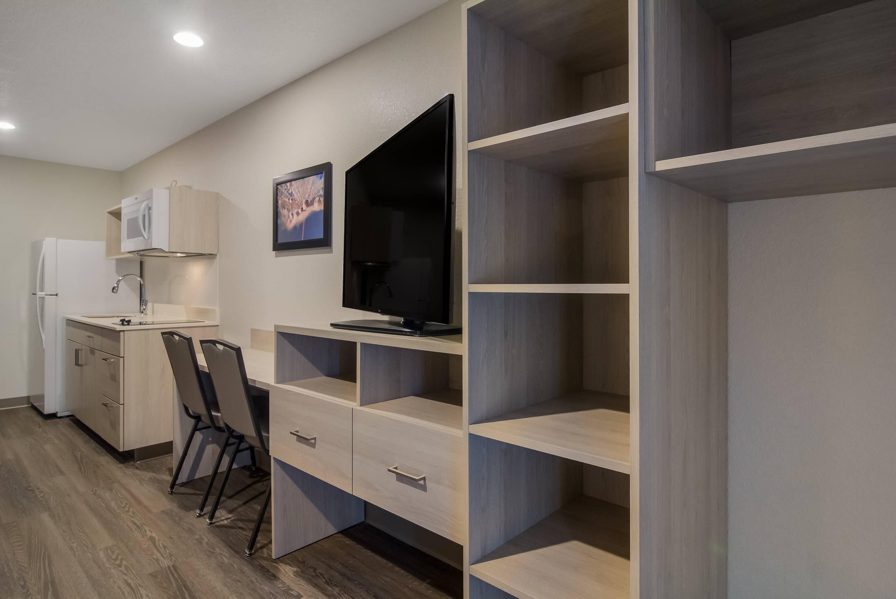 Eine moderne Küche mit Einbau-Mikrowelle, Kühlschrank und Essbereich mit Stühlen.