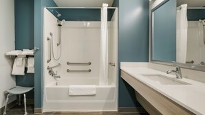 A modern bathroom with a bathtub, shower, and a vanity with a sink. - Woodspring Suites Jacksonville Orange Park (Orange Park)