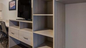 A modern room with a built-in TV, wooden shelving, and a desk area. - Woodspring Suites Jacksonville Orange Park (Orange Park)