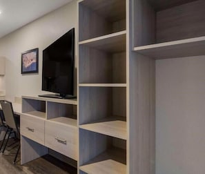 A modern room with a built-in TV, wooden shelving, and a desk area. - Woodspring Suites Jacksonville Orange Park (Orange Park)