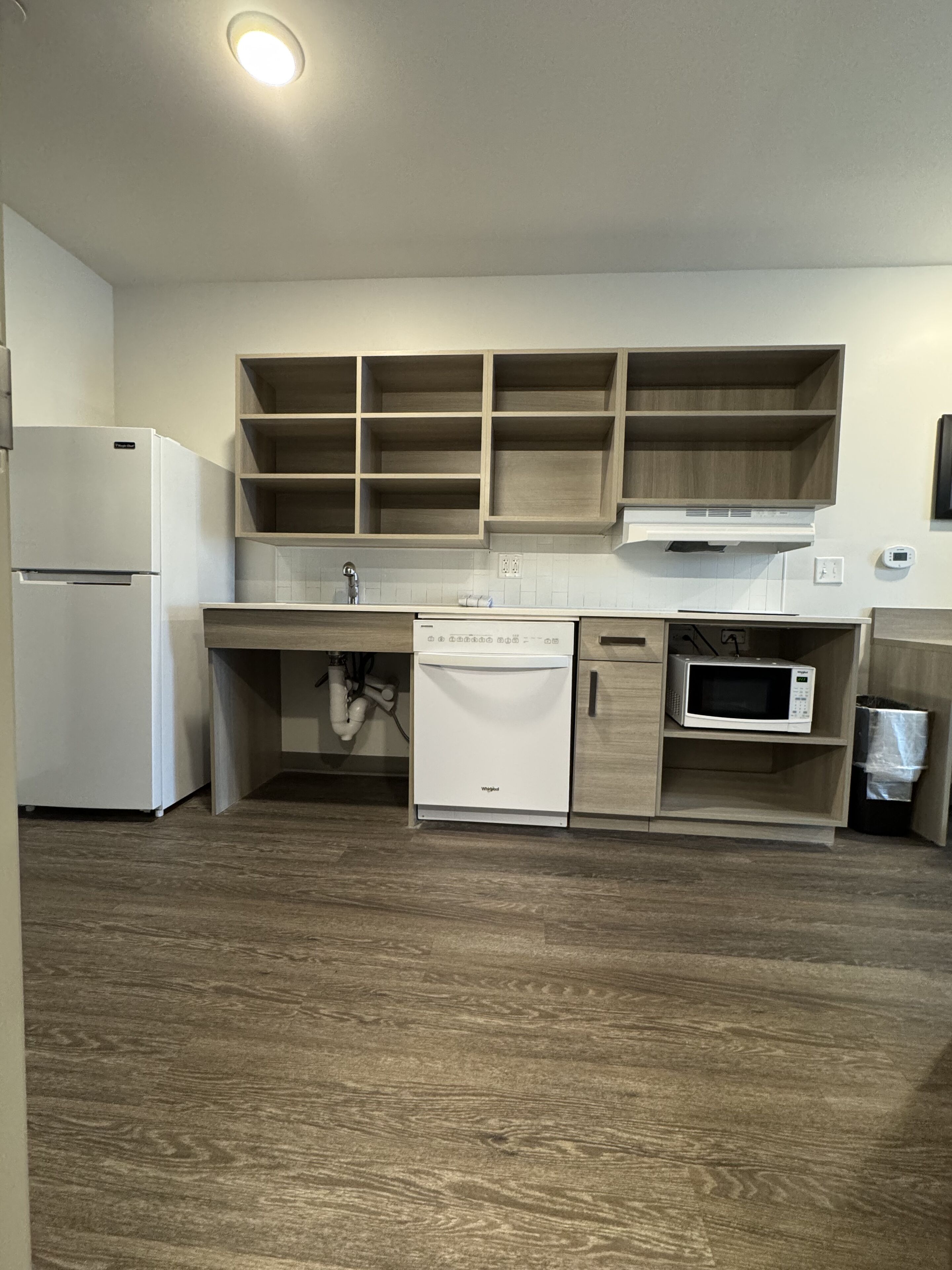 Una cocina compacta equipada con lavavajillas, microondas y refrigerador.
