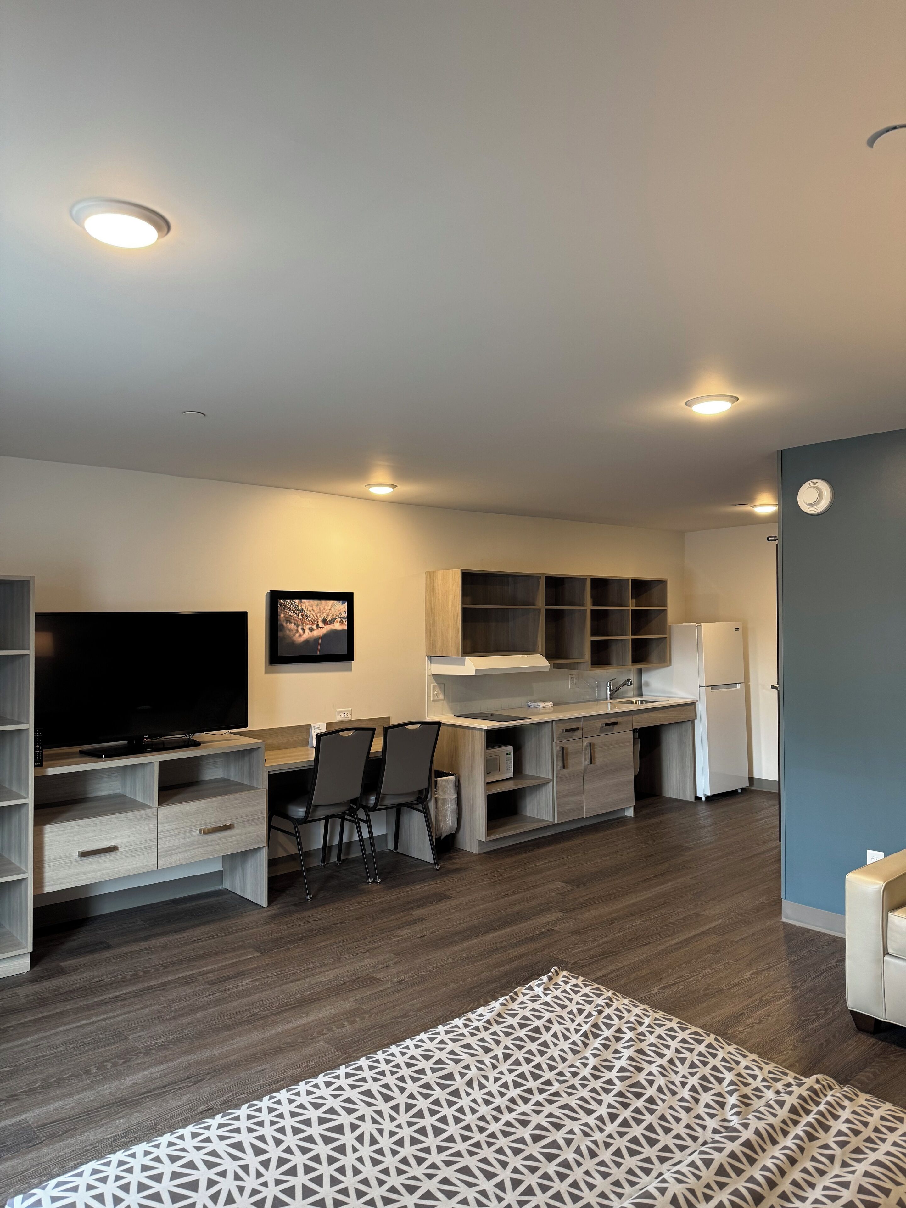 A modern kitchen with built-in appliances, a dining area with chairs, and a flat-screen TV.