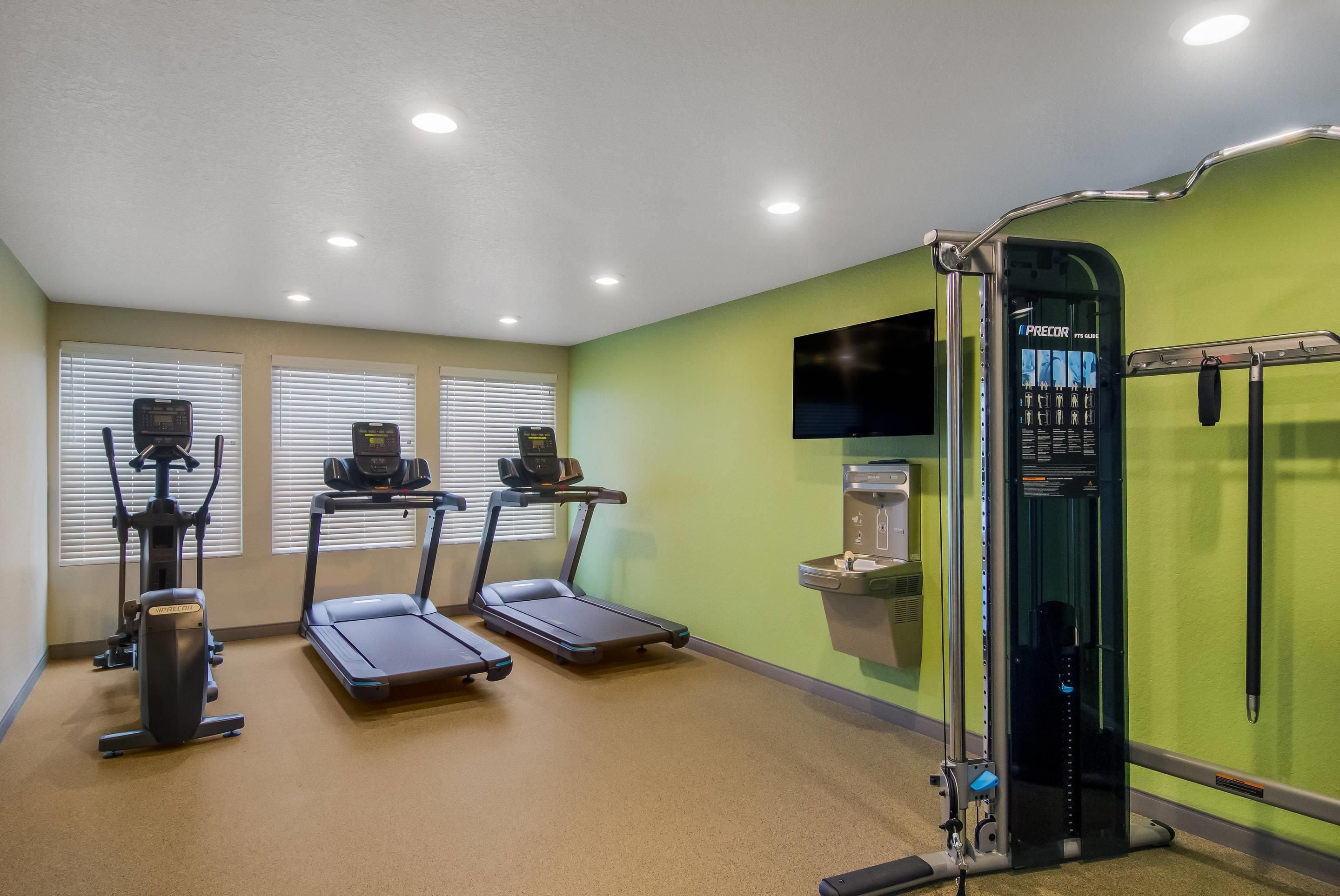 A fitness room with treadmills, a stationary bike, and a weight machine.
