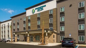 A multi-story hotel with a modern design, featuring a prominent logo and signage. - Woodspring Suites Jacksonville Orange Park (Orange Park)