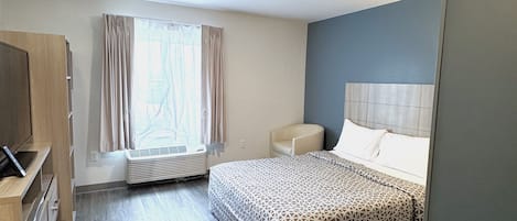 Una habitación de hotel con una cama, un escritorio, una silla y una ventana con cortinas.