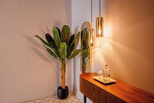 A potted plant, a mirror, a wooden console, and a bottle on a console table.
