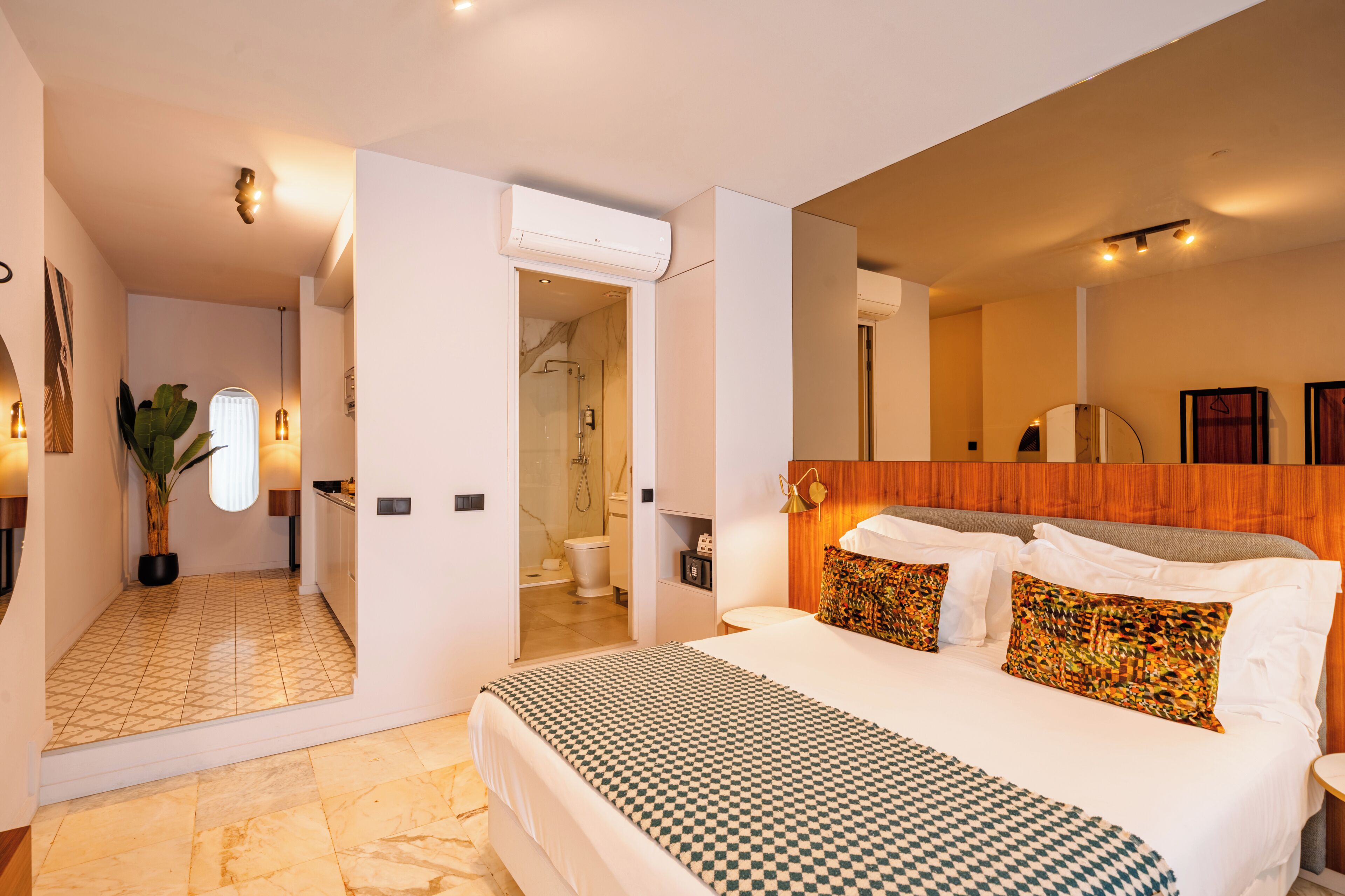 Une chambre d’hôtel avec un grand lit, une salle de bain et un couloir menant à une autre pièce.