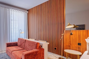 Ein modernes Hotelzimmer mit einer Wandpaneele aus Holz, einer Couch, einem Schreibtisch und einer Lampe.