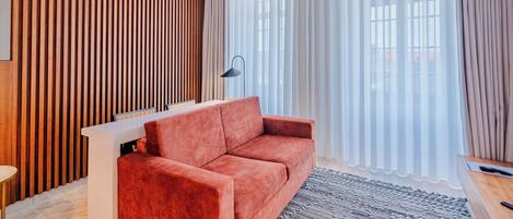 A modern living room with a red sofa, a white side table, and a patterned rug.