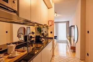 A modern kitchen with a central island, stainless steel appliances, and a view into the living area.