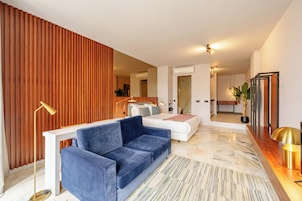 A modern living room with a blue sofa, a white couch, and a wooden accent wall.